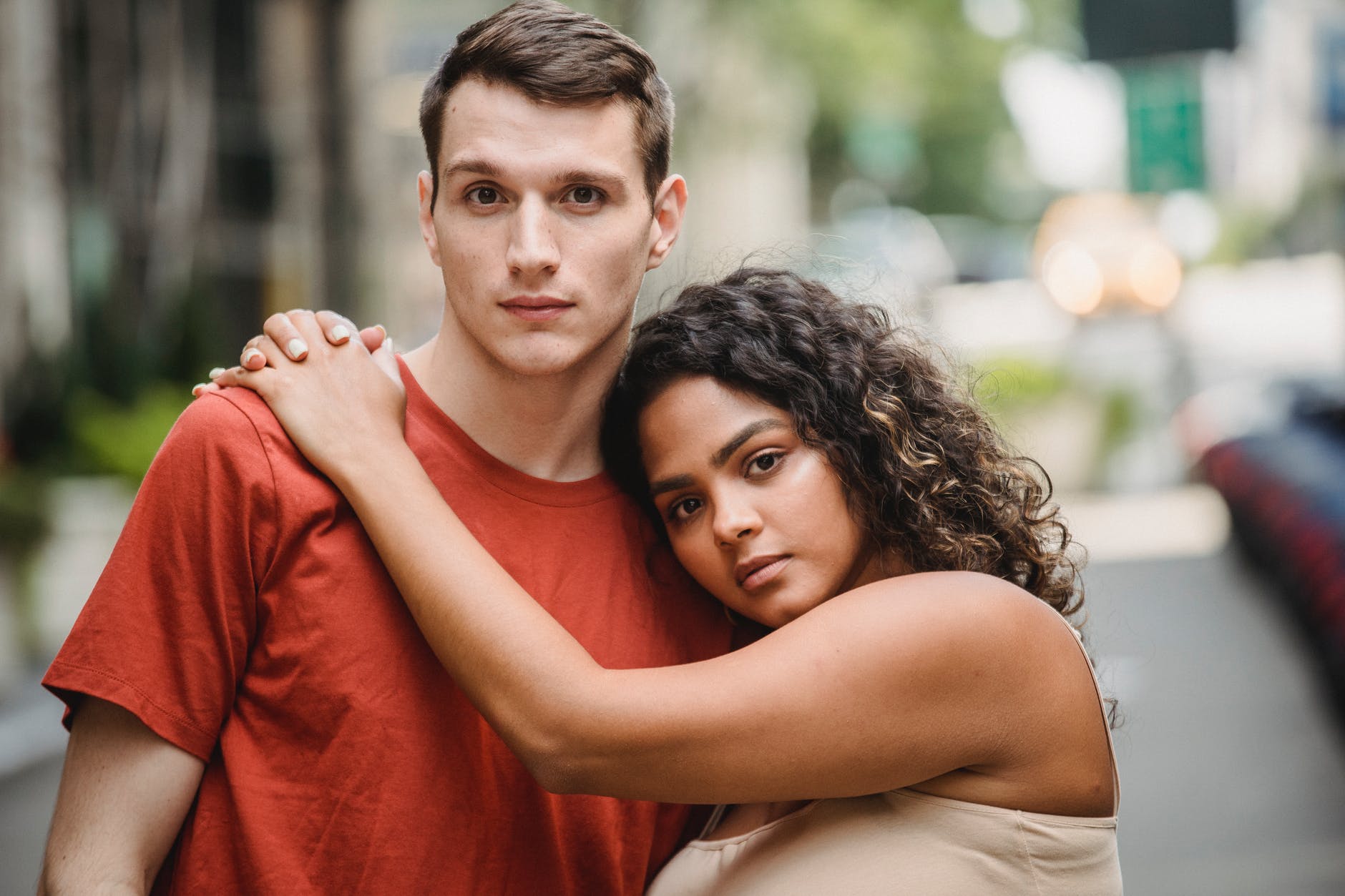 loving ethnic girlfriend hugging boyfriend while standing together on sunny day