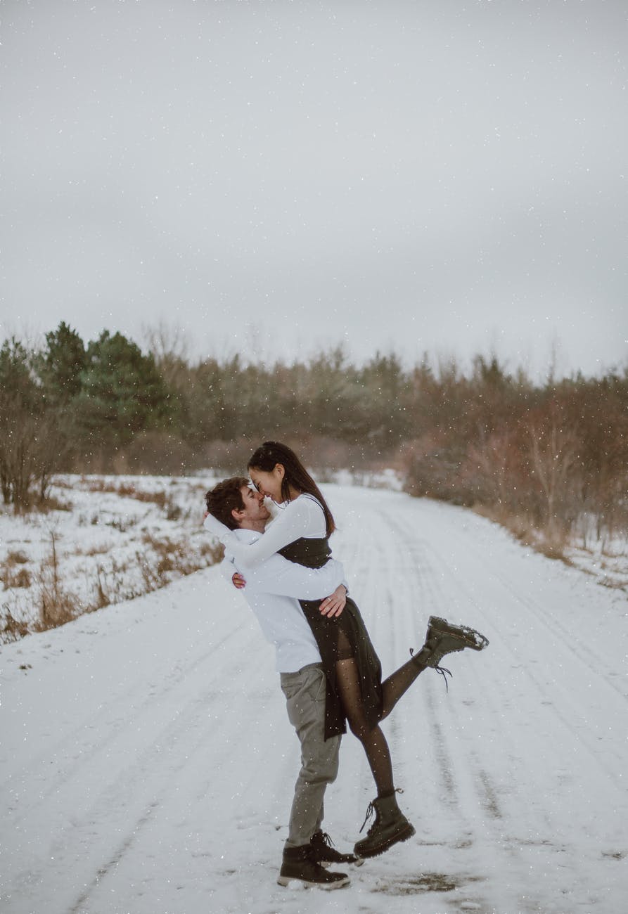 happy multiethnic couple embracing on snowy road