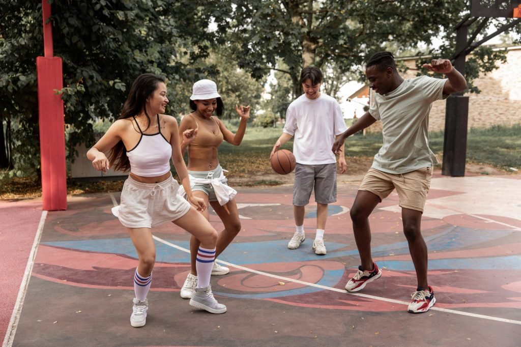 delighted young diverse people dancing on sports ground