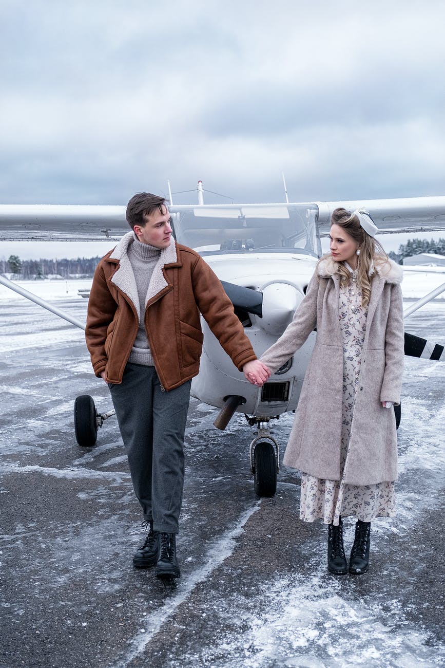 young couple in warm clothes holding hands on airfield