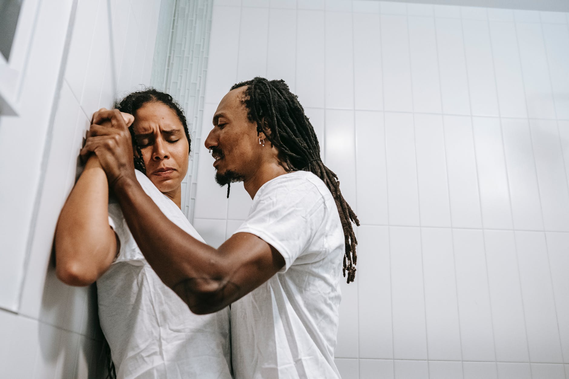 aggressive ethnic man and frightened woman quarreling in bathroom