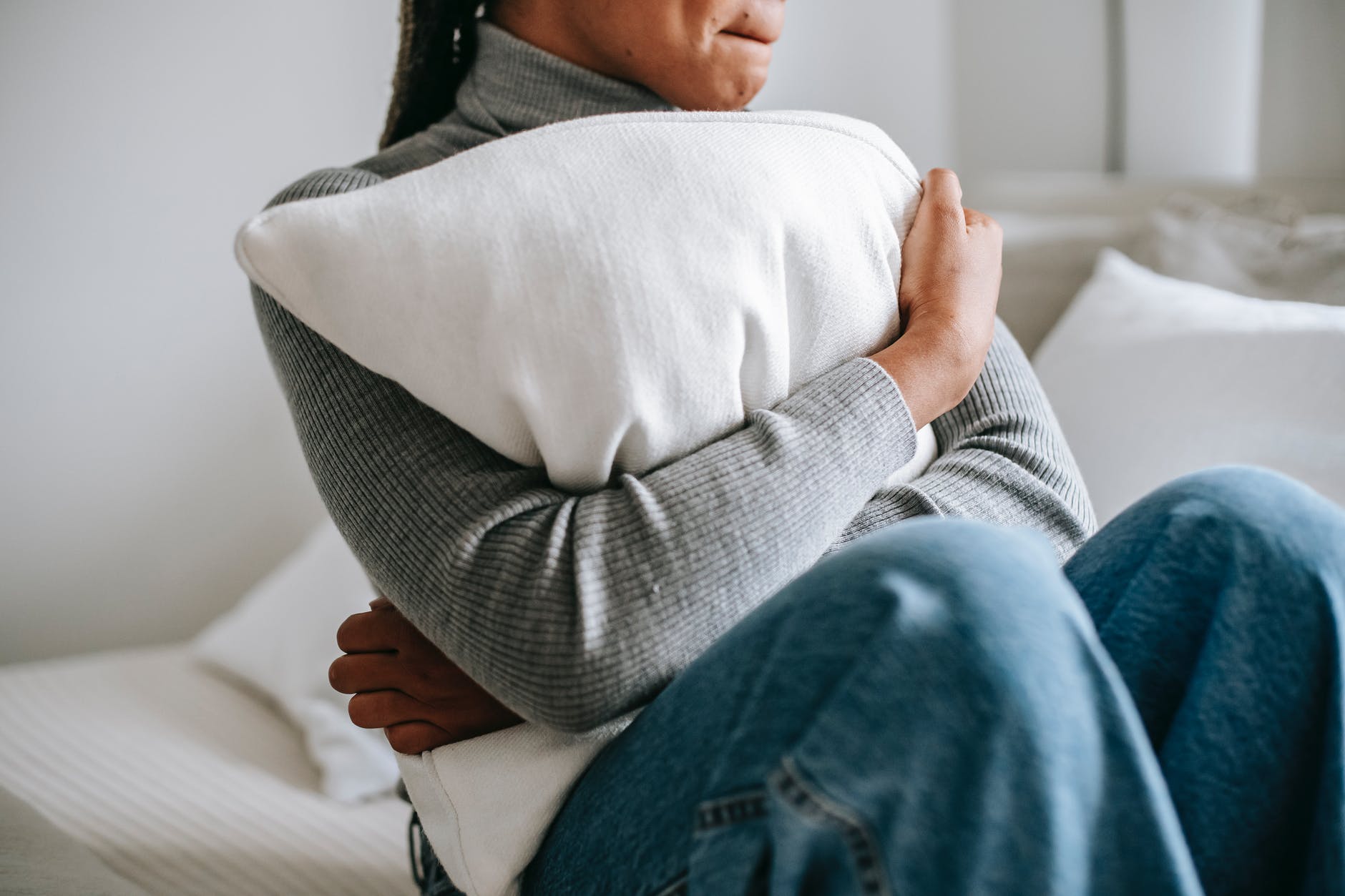 unrecognizable depressed black woman embracing pillow in bedroom