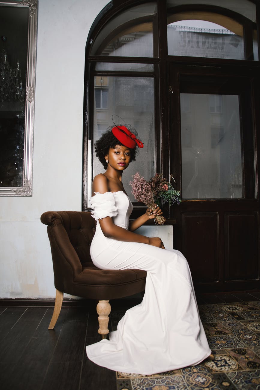 woman in white off shoulder wedding dress sitting in brown fabric sofa chair