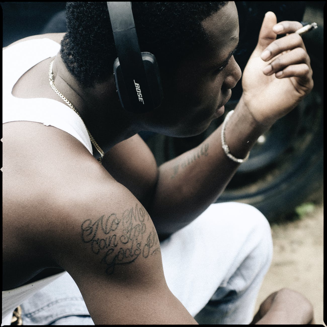 crop informal black man in headphone smoking cigarette on street