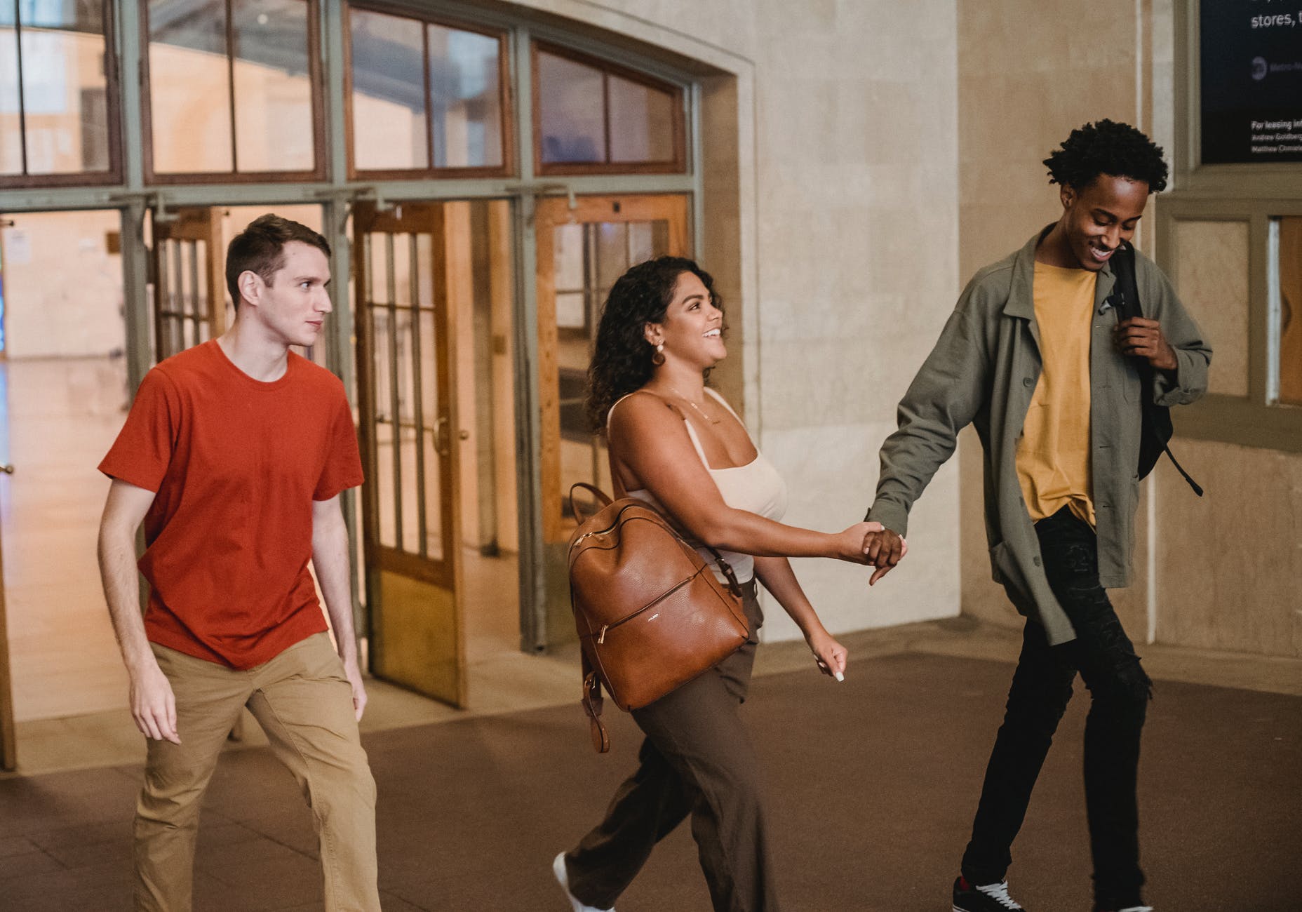 happy young multiethnic couple together with male friend leaving university
