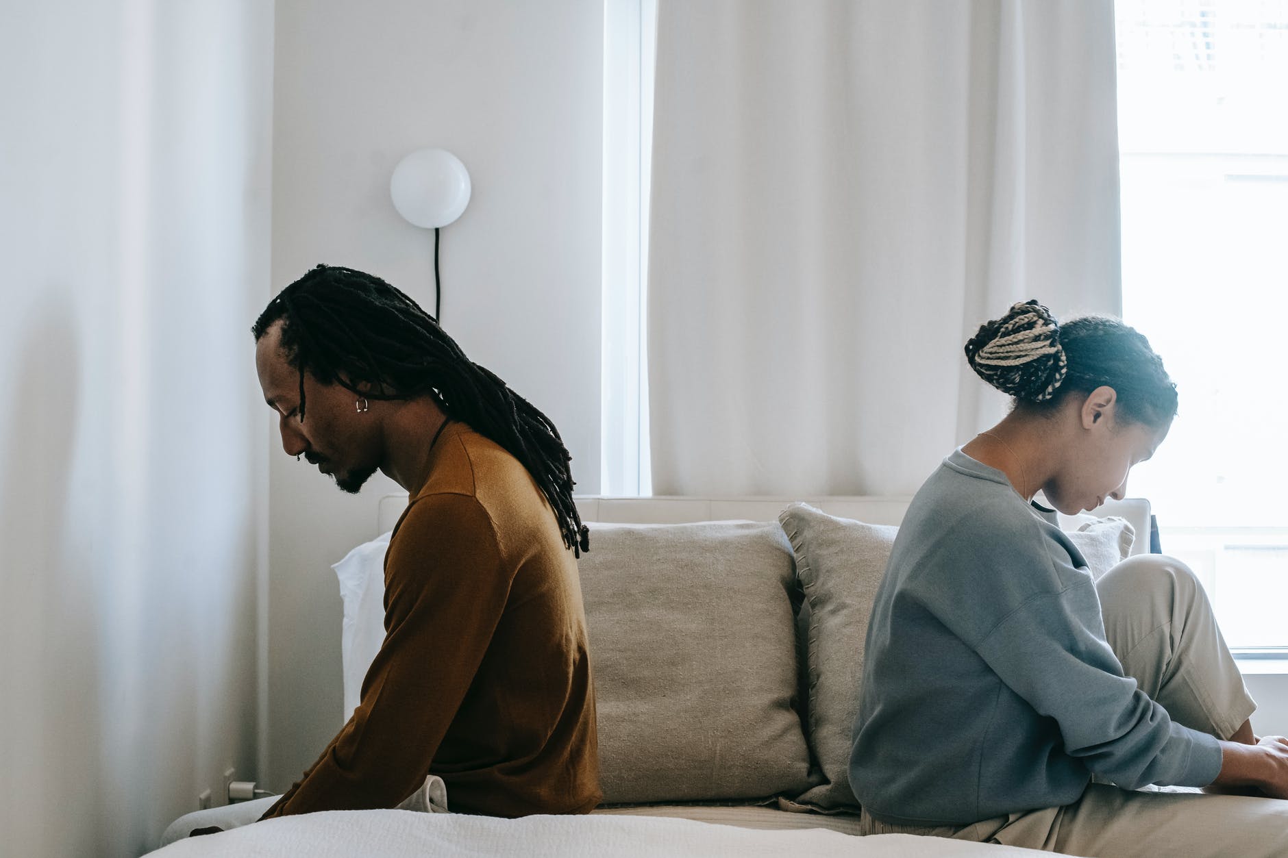 concerned black couple sitting on bed in misunderstanding