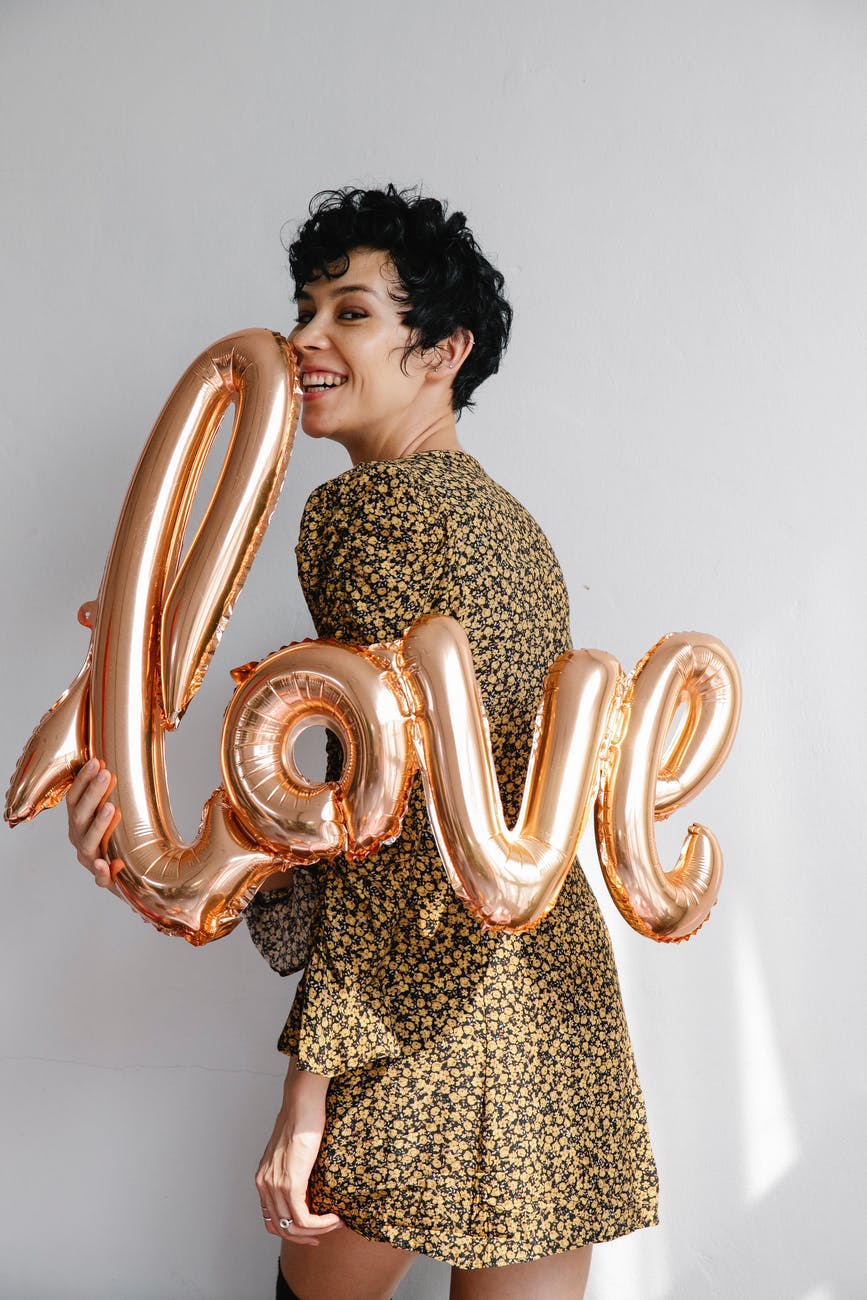 cheerful woman showing festive sparkling balloon with word love